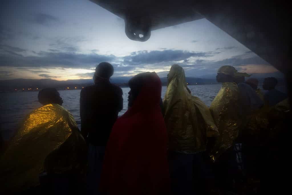 Wrapped in blankets, Sub-Saharan migrants stand on the deck of the Golfo Azzurro rescue vessel after arriving at the port of Messina, in Italy, with more than 299 migrants aboard the ship rescued by members of Proactive Open Arms NGO, on Sunday, Jan. 29, 2017. (AP Photo/Emilio Morenatti)
