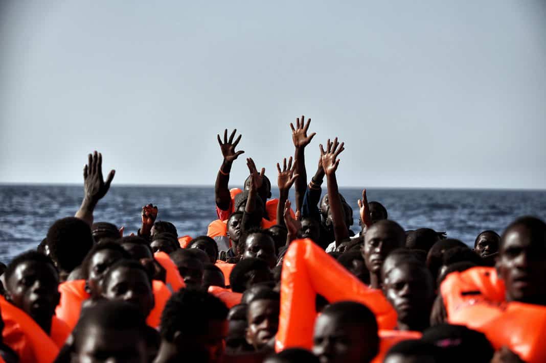 TOPSHOT - Migrants wait to be rescued as they drift in the Mediterranean Sea some 20 nautical miles north off the coast of Libya on October 3, 2016. Italy coordinated the rescue of more than 5,600 migrants off Libya, three years to the day after 366 people died in a sinking that first alerted the world to the Mediterranean migrant crisis. / AFP / ARIS MESSINIS (Photo credit should read ARIS MESSINIS/AFP/Getty Images)