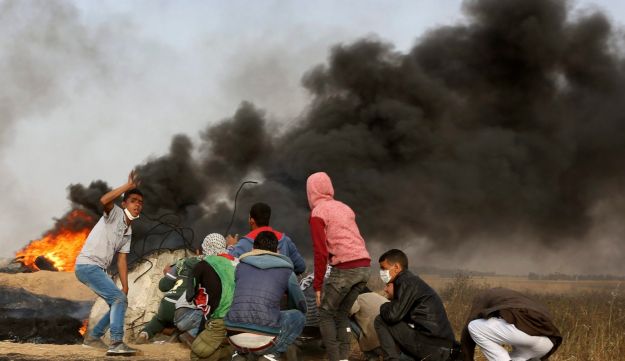 Palestinian protesters cover during clashes with Israeli troops along Gaza's border with Israel, east of Khan Younis, Gaza Strip, Thursday, April 5, 2018