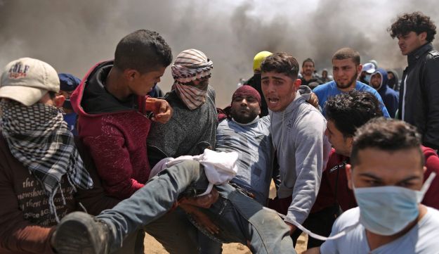 Palestinian men carry an injured protester after clashes with Israeli forces at the Israel-Gaza border, April 6, 2018.